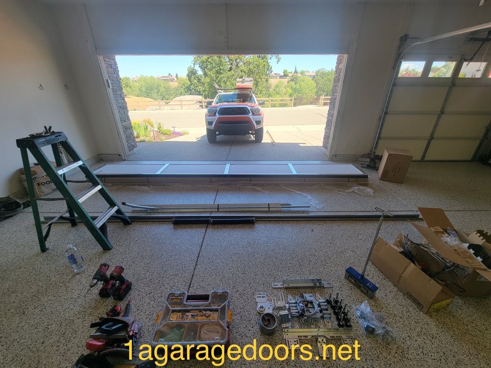 Garage door panels and installation hardware laid out inside a garage