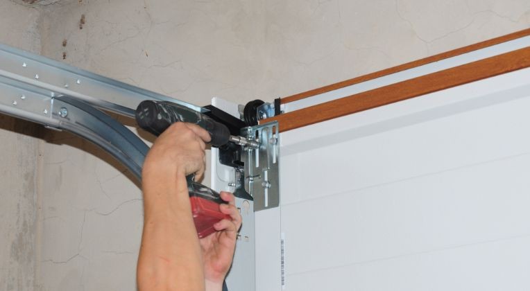 Garage door track mounting bracket and roller being inspected